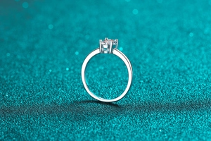 Vista laterale macro di un anello solitario moissanite a quattro griffe su sfondo glitter