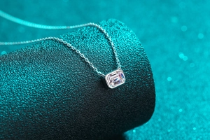 Detail of emerald cut moissanite pendant in bezel setting on a fine S925 silver chain