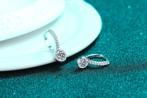 Close-up of S925 sterling silver hoop earrings with round moissanite on green texture