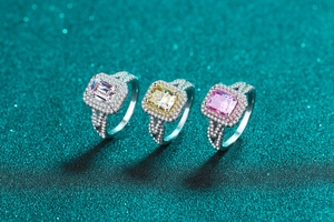 Detailed view of emerald-cut pink and yellow moissanite rings with halo silver bands