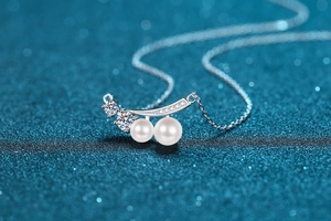 Macro shot of S925 sterling silver necklace featuring moissanite and two white pearls