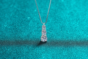 Gros plan d'un collier en argent S925 avec trois moissanites graduées sur paillettes bleues