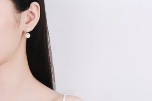Close-up of S925 silver double pearl earrings with Moissanite halo on female model ear