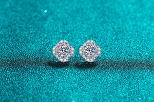Macro shot of S925 silver moissanite earrings with halo design on teal glitter backdrop