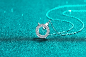 Détail du pendentif en argent 925 et moissanite sur une surface verte scintillante