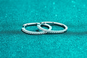 Macro shot of S925 sterling silver hoop earrings with pave-set moissanite on blue background