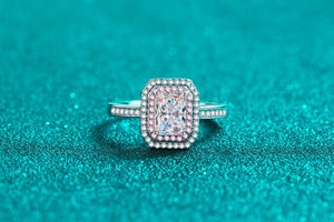 Macro shot of a radiant cut moissanite ring with a double halo of pink and white stones