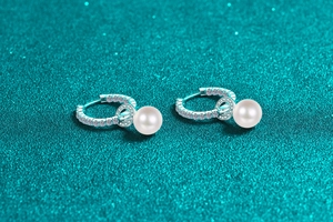 Macro shot of S925 silver hoop earrings with small moissanite and dangling round pearls