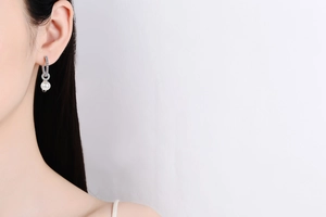 Close-up of S925 silver earrings with freshwater pearl and sparkling moissanite on ear