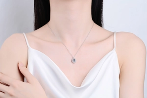 Macro shot of S925 silver necklace with oval pendant and blue moissanite on female collarbone