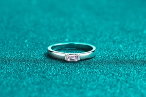 Macro view of emerald-cut moissanite stone in horizontal claw setting on silver band