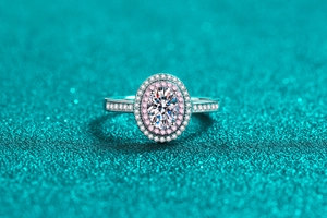 Macro detail of oval moissanite ring with pink and white halo on blue glitter background