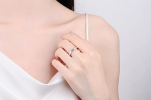 Elegant emerald cut light blue moissanite ring on model in white silk dress