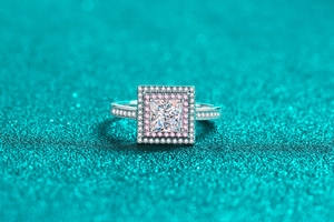 Macro view of princess cut silver ring featuring double halo with pink and clear stones