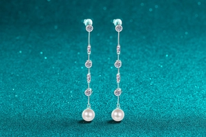 Dettaglio di orecchini pendenti in argento S925 con moissanite e perle bianche