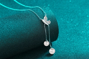 Détail du collier papillon en argent avec cristaux et deux glands en perles