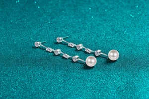Dettaglio di orecchini a pendente in argento con nappe di pietre e perle bianche