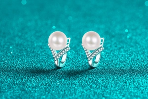 Macro detail of S925 silver pearl earring with V-shaped setting and pavé zircon stones
