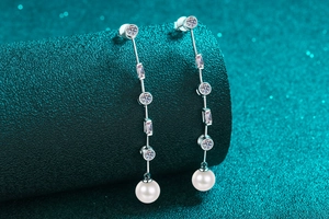 Dettaglio macro di orecchini a nappa in argento S925 con zircone e perle rotonde bianche