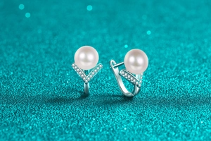 Detailed view of S925 silver pearl earrings with sparkling moissanite on green glitter