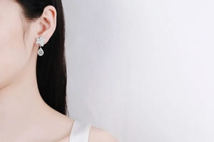 Close-up of star-shaped and pear-cut moissanite silver earrings worn by a model