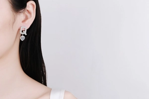 Detailed view of S925 sterling silver heart-shaped moissanite earrings worn by a model
