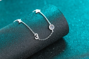 Detailed view of S925 silver bracelet with moissanite charms on textured pedestal