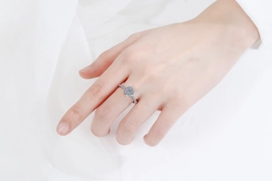 Gros plan d'une bague halo en moissanite argent S925 portée avec tissu de soie