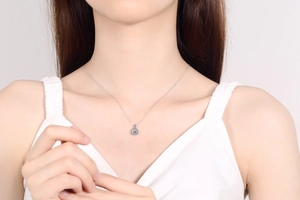 Detail view of S925 sterling silver necklace with blue moissanite pendant on a model