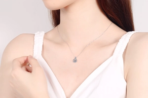 Close-up of S925 silver necklace featuring a dancing blue moissanite pendant on a model