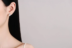 Detailed close-up of a silver freshwater pearl earring with sparkling zircons on model