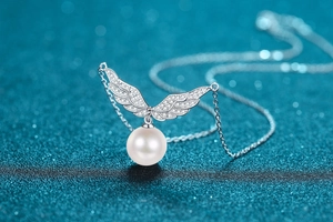 Macro shot of 925 sterling silver angel wing pendant with diamond inlay and white pearl