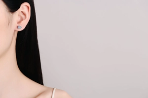 Close-up of a square-cut moissanite stud earring on a female model with black hair