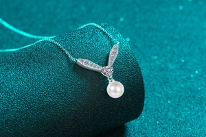Détail macro du pendentif en V avec moissanite, pierre en cœur et perle d'eau douce ronde