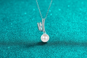 Macro shot of silver spiral pearl pendant with zircon inlay on blue glitter background