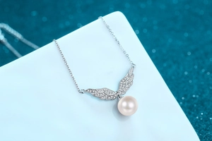 Detail of angel wing pendant with small crystals and a round freshwater pearl charm