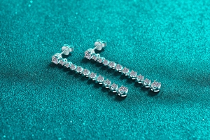 Detailed view of silver drop earrings featuring vertical moissanite stones and stud backs