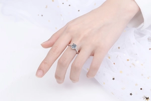 Detail of a four-prong S925 silver moissanite ring worn on hand with mesh background