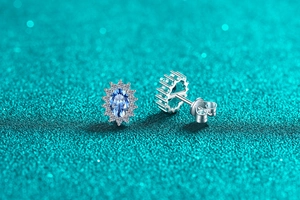 Macro view of S925 silver halo stud earrings with oval blue sapphire and pavé diamonds
