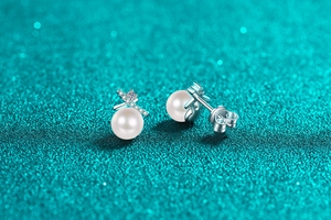 Macro detail of S925 silver pearl stud earrings with cross design and sparkling stones