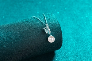 Detail of S925 silver necklace featuring a round pearl pendant with pavé-set zircons