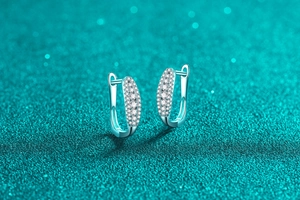 Detail of silver huggie earrings with triple-row pavé-set moissanite on sparkly teal background