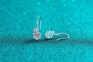 Macro shot of S925 silver moissanite drop earrings with classic six-prong setting on blue base