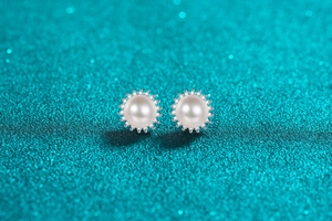 Macro shot of S925 silver sunflower stud earrings with pearl and moissanite stones