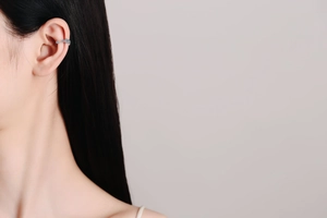 Dettaglio di ear cuff in argento con pietre blu indossato su un orecchio non forato