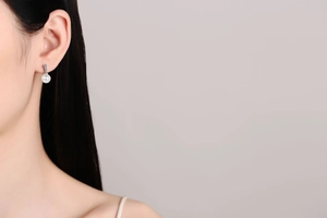 Close-up of elegant S925 silver pearl drop earrings worn on ear with sparkling moissanite detail