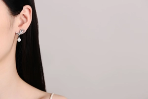 Close-up of S925 silver bow earrings with moissanite and 8mm pearl on model
