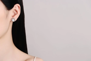 Detail view of flower-shaped pearl earrings with sparkling stones on the ear lobe