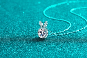 Dettaglio macro del ciondolo in argento con moissanite su sfondo glitter blu