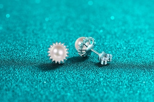 Macro detail of S925 silver sunflower pearl earrings with moissanite halo on blue background